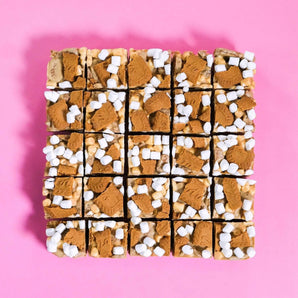 Biscoff Rocky Road from Crumbs & Doilies topped with Biscoff chunks and mini marshmallows on pink background.